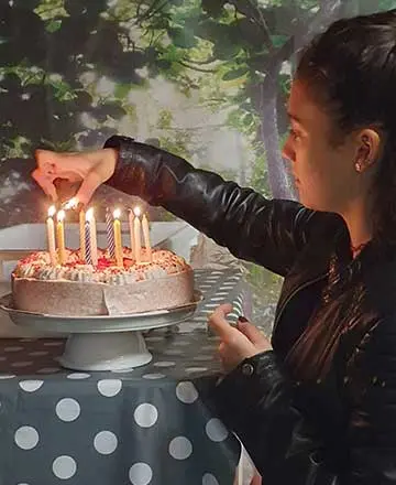 Mädchen zündet die Kerzen einer Geburtstagstorte in der Fossilienwelt an.