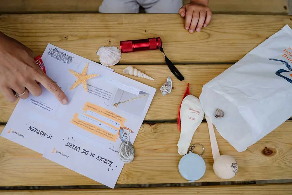 Kinder betrachten Fundstücke und Arbeitsblatt zu Fossilien in der Fossilienwelt.