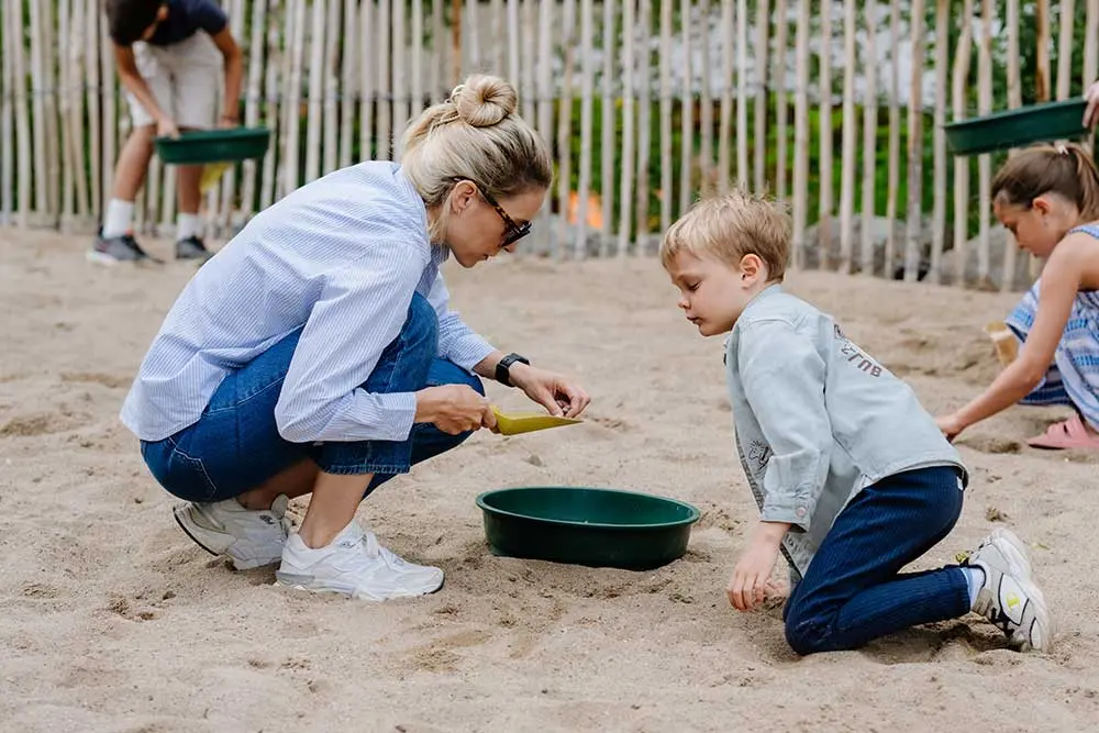 Kinder und Erwachsene suchen gemeinsam im Sand der Haibucht nach Fossilien