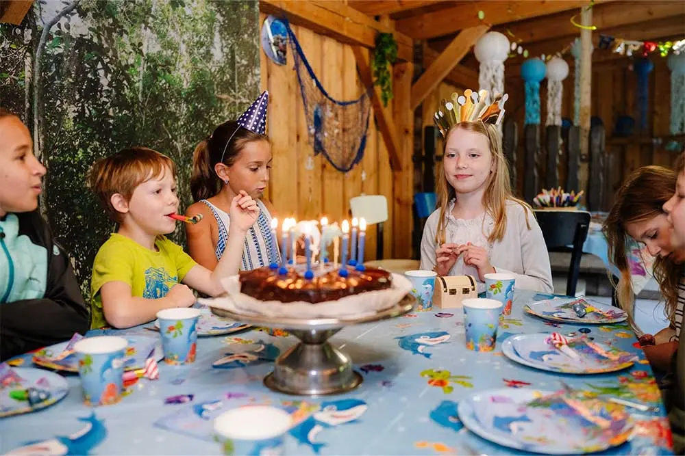 Kinder feiern einen Geburtstagstisch in der Fossilienwelt.