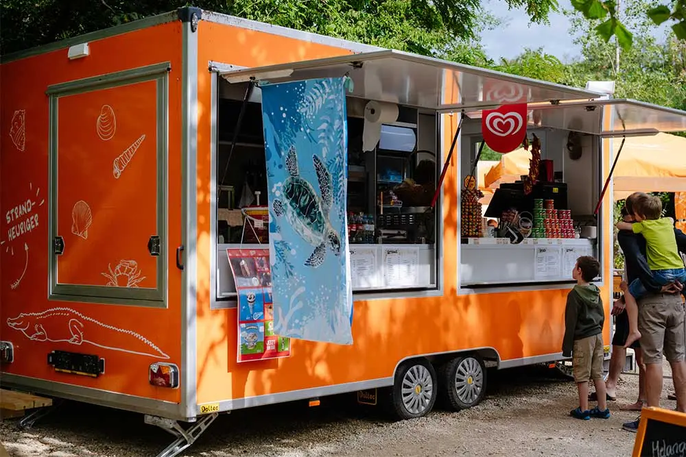 Imbisswagen „Strandheuriger“ mit Gästen vor dem Verkaufsfenster