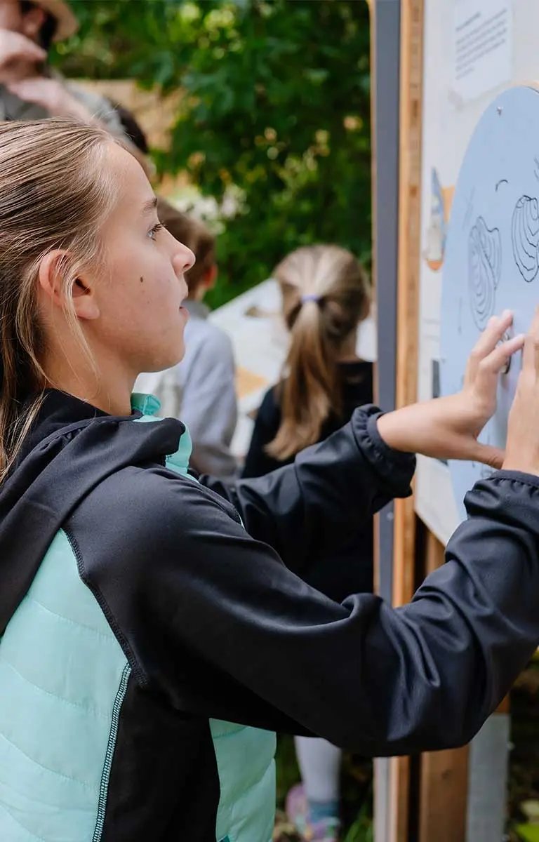 Schülerin entdeckt eine interaktive Station im Außenbereich der Fossilienwelt.