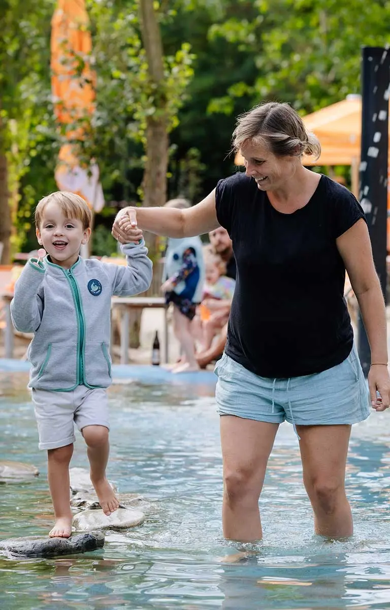 Kinder und Erwachsene waten gemeinsam durch das Urmeer-Becken in der Fossilienwelt.